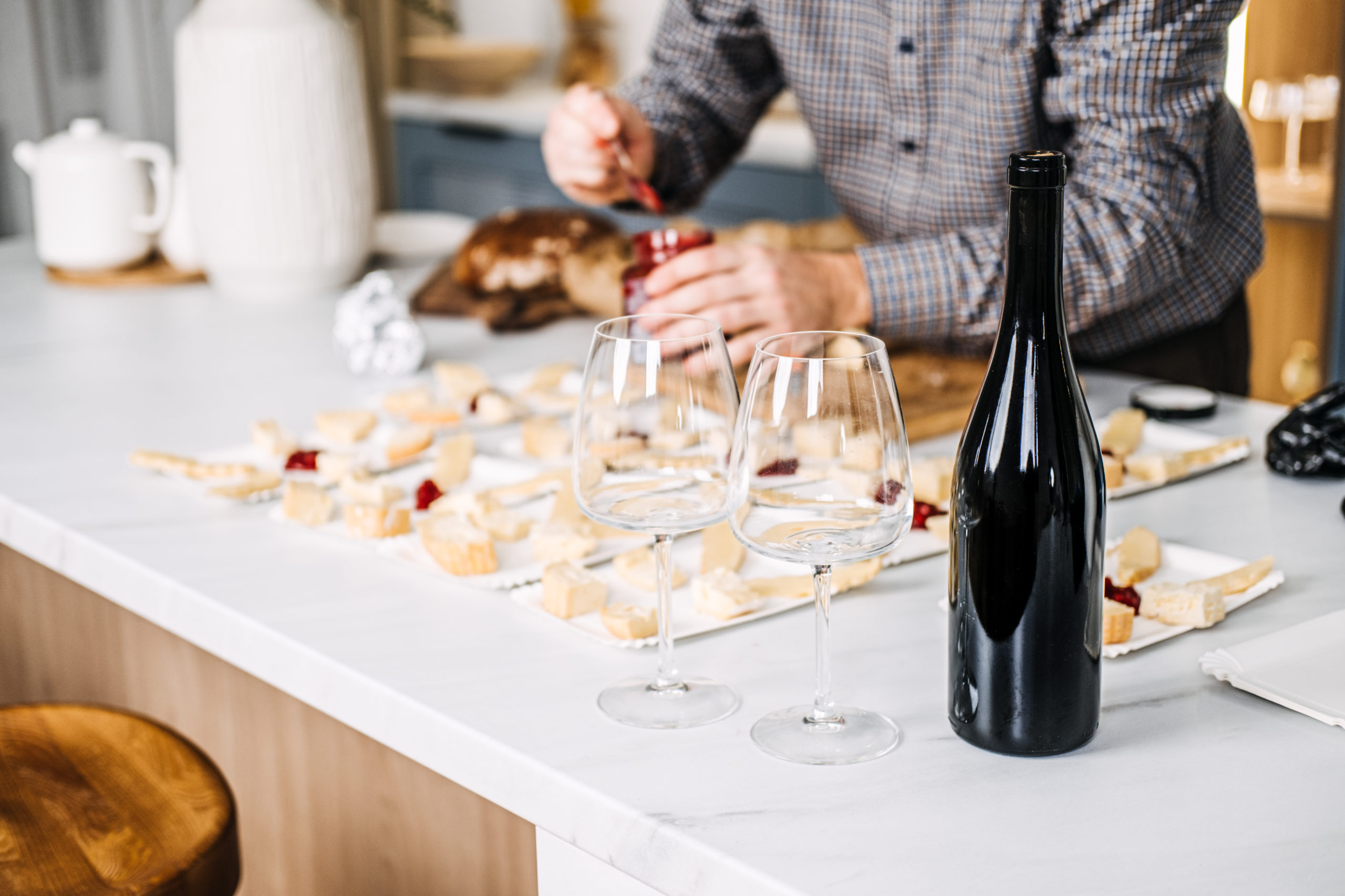 Wine Tasting Preparation with Cheese Pairings. Sommelier prepares for a wine tasting event, carefully pairing various cheeses with wines, featuring an unopened bottle and elegant glasses